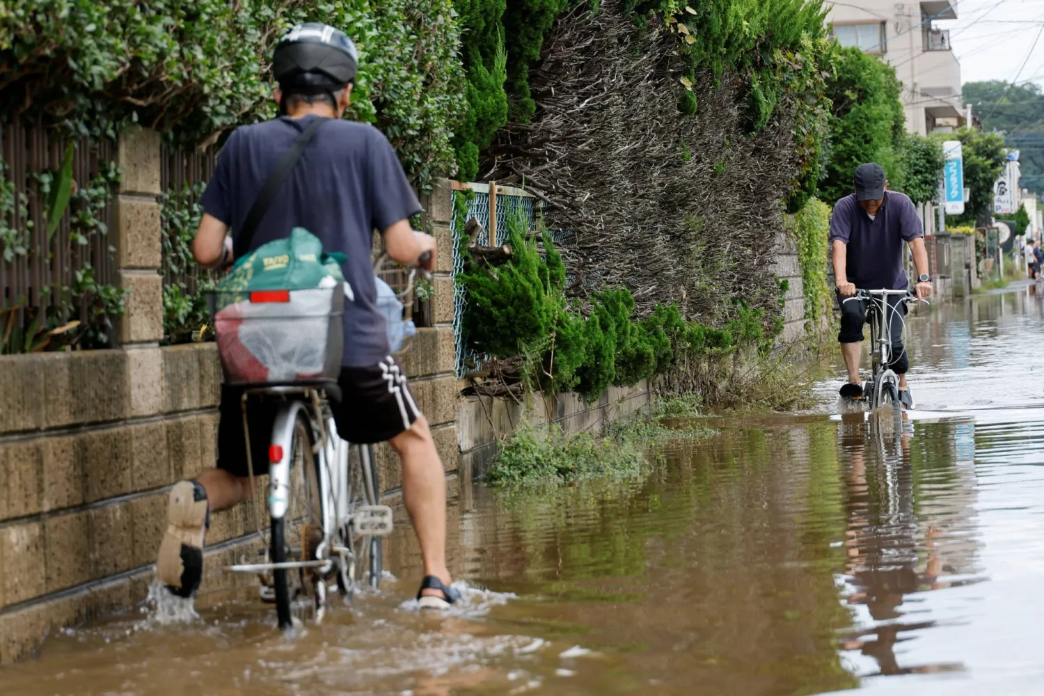 Residents cycle through a flooded street after Typhoon Dujuan brought torrential rain to Sakura, Chiba prefecture, Japan, September 22, 2026. REUTERS/Kim Kyung-Hoon