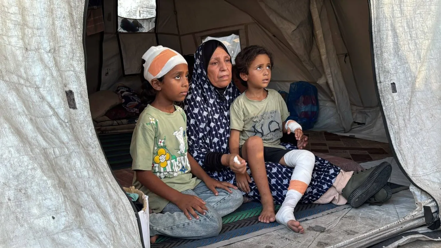 Palestinian Umm Iyad Azzam sits with her two grandchildren who survived the collapse of the Al-Saada building in Gaza (Asharq Al-Awsat) 