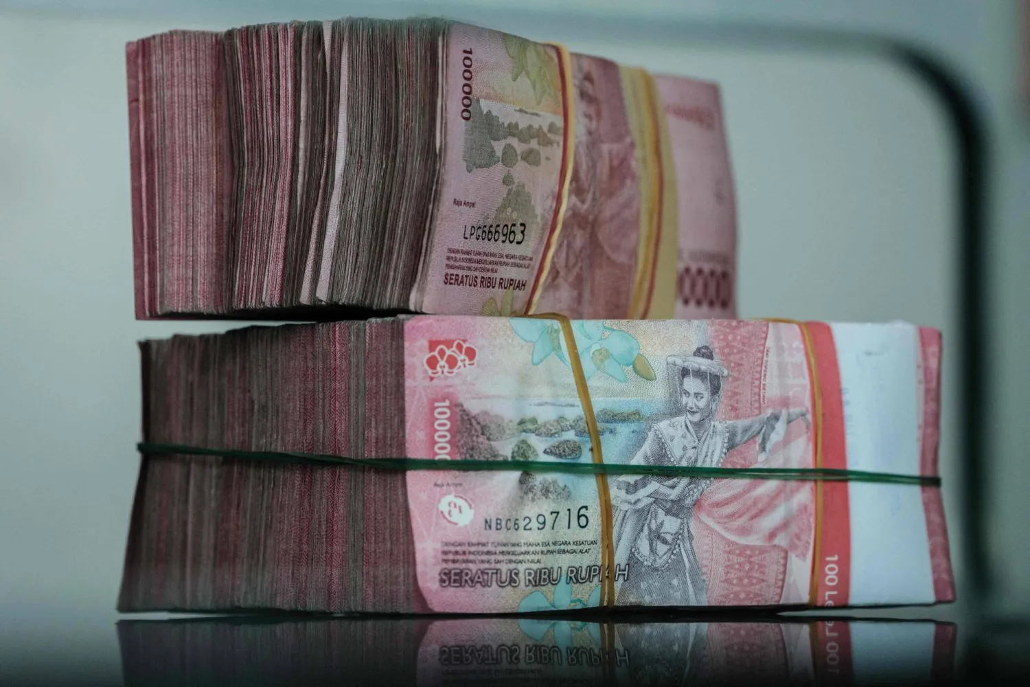 أوراق نقدية من الروبية الإندونيسية مُكدّسة في مكتب لصرافة العملات في جاكرتا (أ.ف.ب)