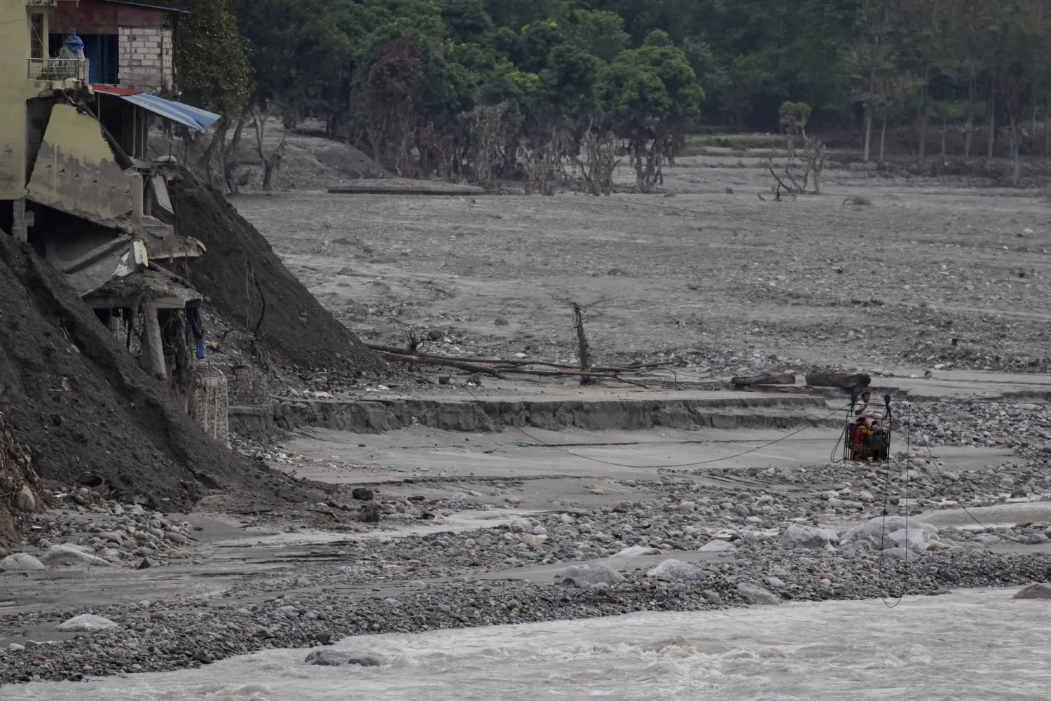 People hold onto a cage on a makeshift zip line as they cross the Trishuli River from Devighat following deadly flash floods that damaged bridges and temporarily stranded residents, in Nuwakot district, Nepal, September 21, 2026. (Reuters)