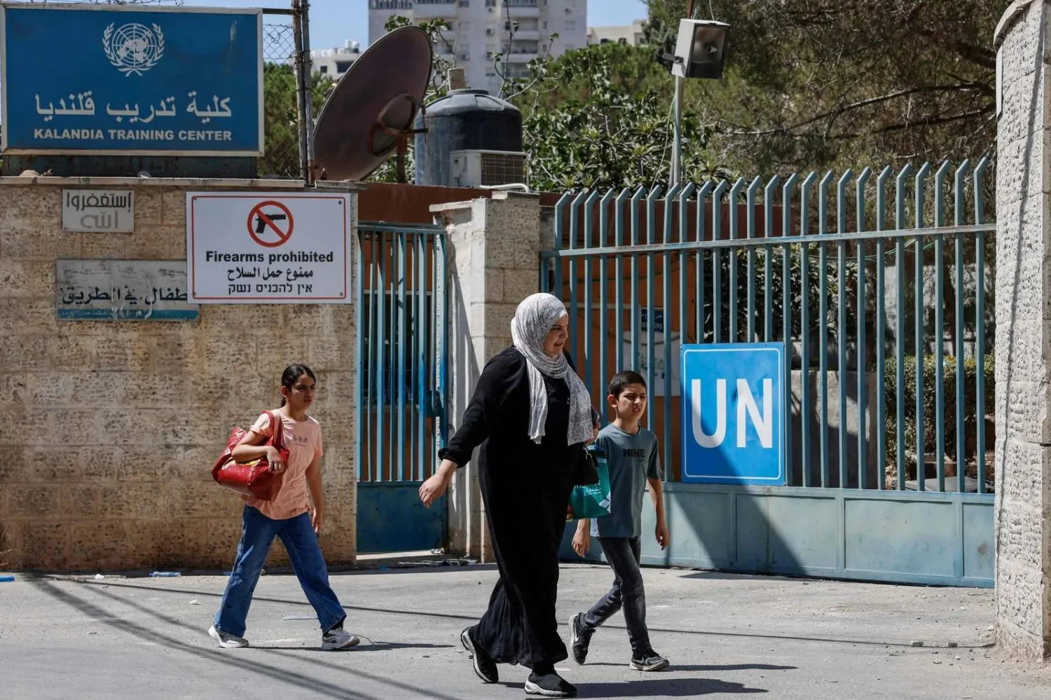 People walk past the UNRWA Vocational Training Center, where Israeli security forces have remained since raiding the facility on August 25, at the Qalandia refugee camp, south of the Israeli-occupied West Bank city of Ramallah, on August 27, 2026. (Photo by Zain JAAFAR / AFP) (AFP) 