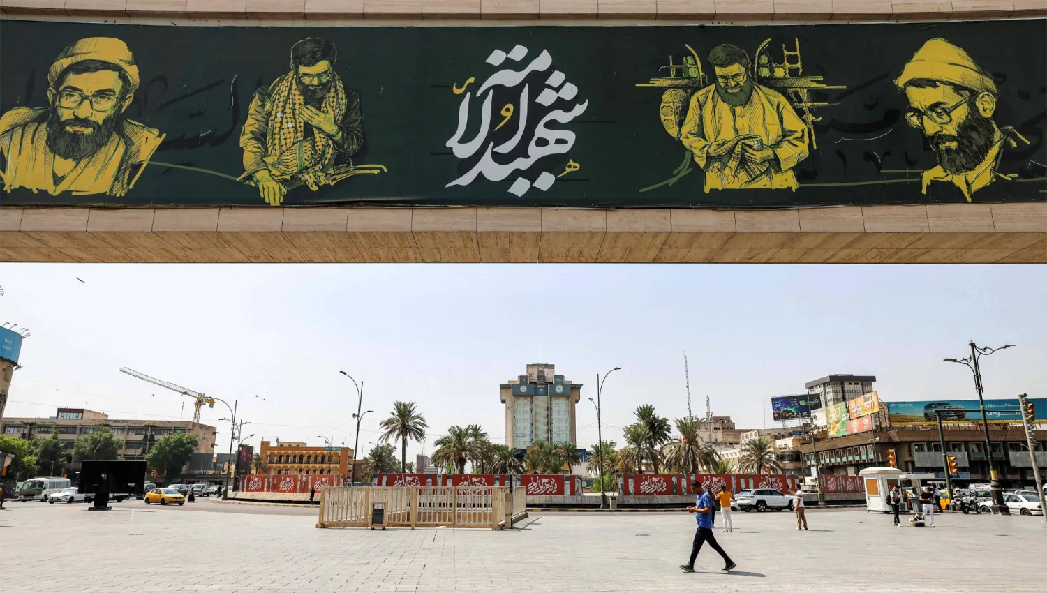 People walk near a giant billboard depicting portrayals of Iran's slain supreme leader Ali Khamenei through various periods in his life, in Baghdad's central Tahrir Square on September 22, 2026. (Photo by AHMAD AL-RUBAYE / AFP)