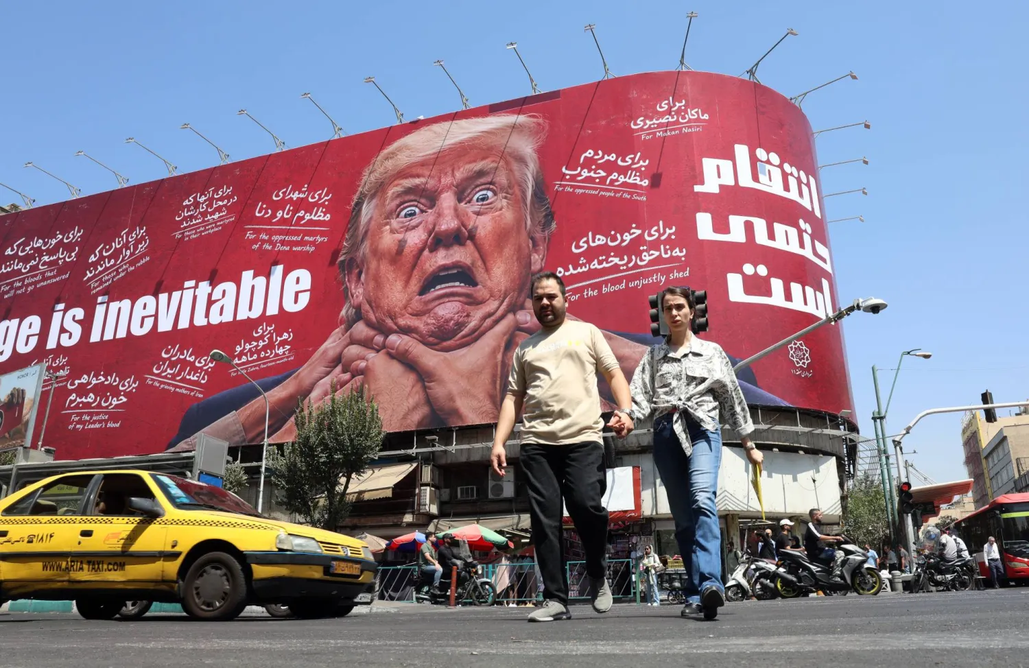 إيرانيون يمرون قرب لوحة مناهضة للرئيس الأميركي دونالد ترمب في طهران (إ.ب.أ)