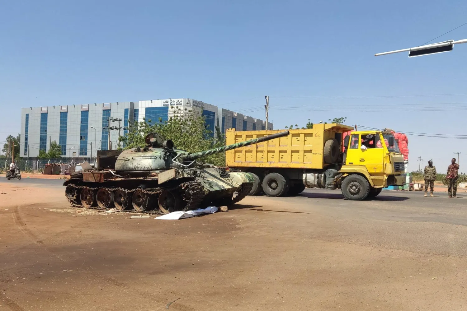 شاحنة تمر بجوار دبابة في مدخل ود مدني بالسودان خلال فبراير 2025 (أ.ف.ب)
