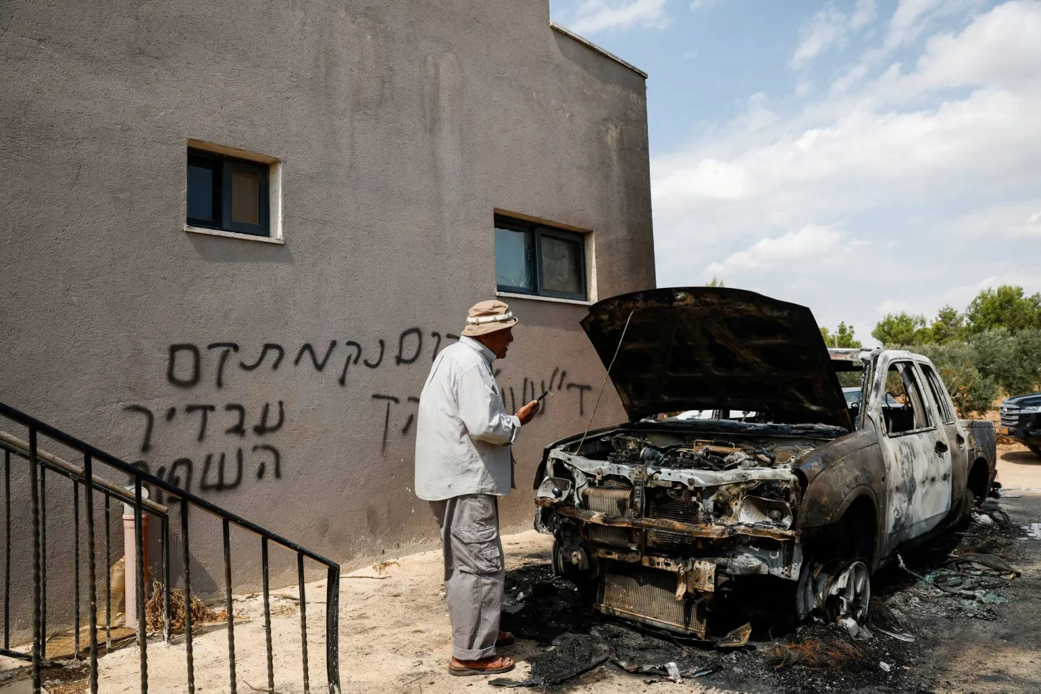 فلسطيني يفحص آثار الدمار يوم الاثنين بعد هجوم لمستوطنين إسرائيليين على قرية قرب رام الله في الضفة الغربية المحتلة (رويترز)