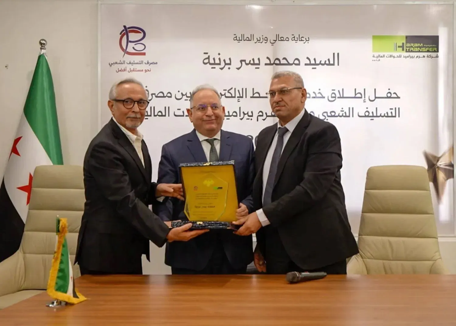 Syrian Finance Minister Mohammed Yisr Barnieh participates in the launch of an electronic link between the Popular Credit Bank and Al-Haram Transfer Company (minister’s account)