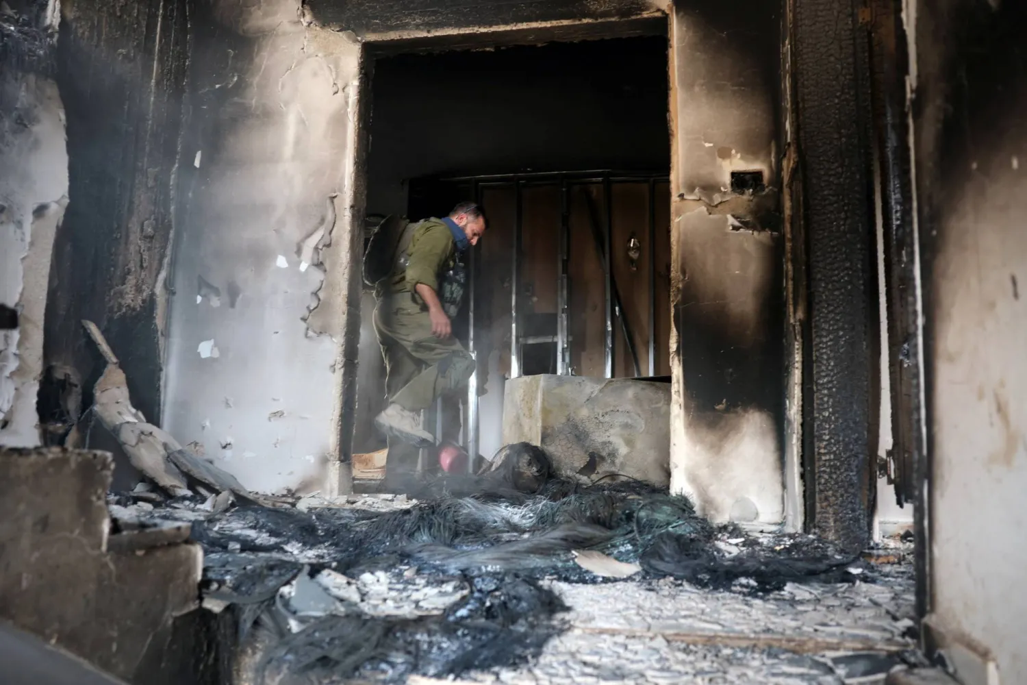 جندي إسرائيلي داخل منزل مملوك لفلسطينيين في الضفة الغربية بعد تعرضه لهجوم وإحراقه من قبل مستوطنين إسرائيليين يوم الثلاثاء (رويترز)