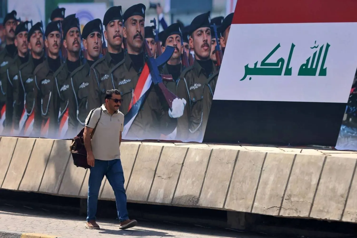 An Iraqi man walks past a sign posted along a street in Baghdad on Sept. 29, 2026, as the international coalition’s mission against ISIS comes to an end. (AFP) 