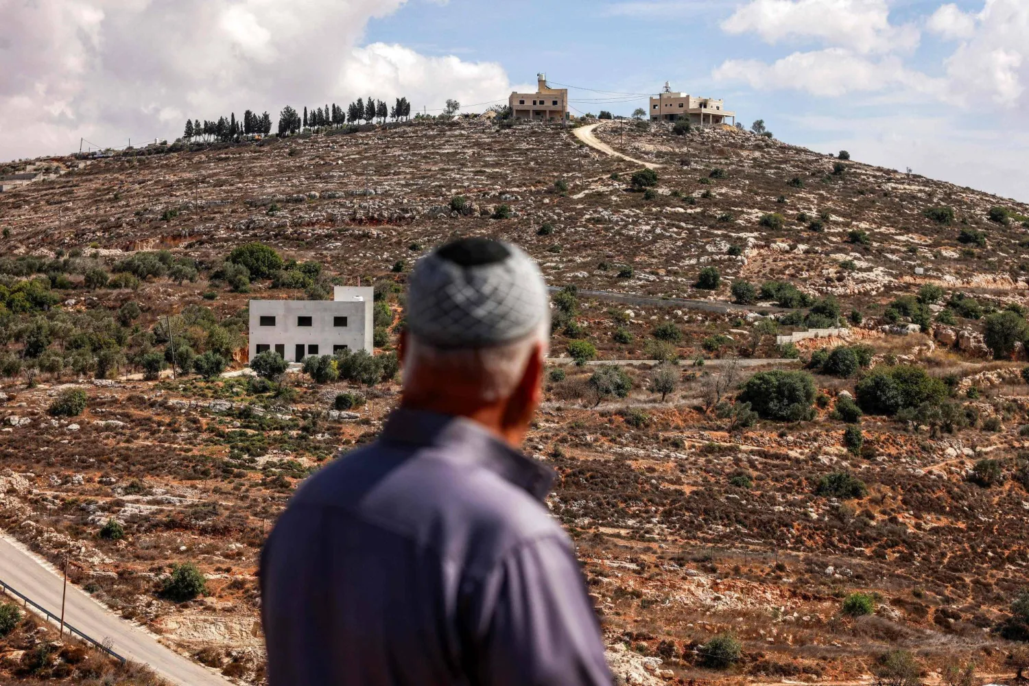 TOPSHOT - Mahmoud al-Toubasi, a 60-year-old Palestinian who was displaced from his home months earlier following an attack by Israeli settlers, stands from a distance looking at his house in the Palestinian village of Jalud, south of Nablus in the Israeli-occupied West Bank, on September 29, 2026. (Photo by Zain JAAFAR / AFP)