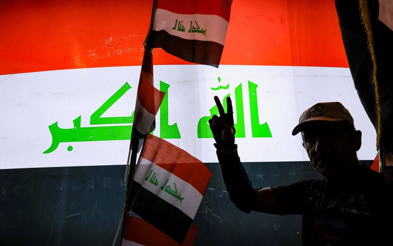 A man gestures in front of a display of the Iraqi flag while celebrating the withdrawal of US-led coalition forces from Iraq, ending a military presence that began after the 2003 US-led invasion, in Baghdad, Iraq, September 30, 2026. (Reuters) 