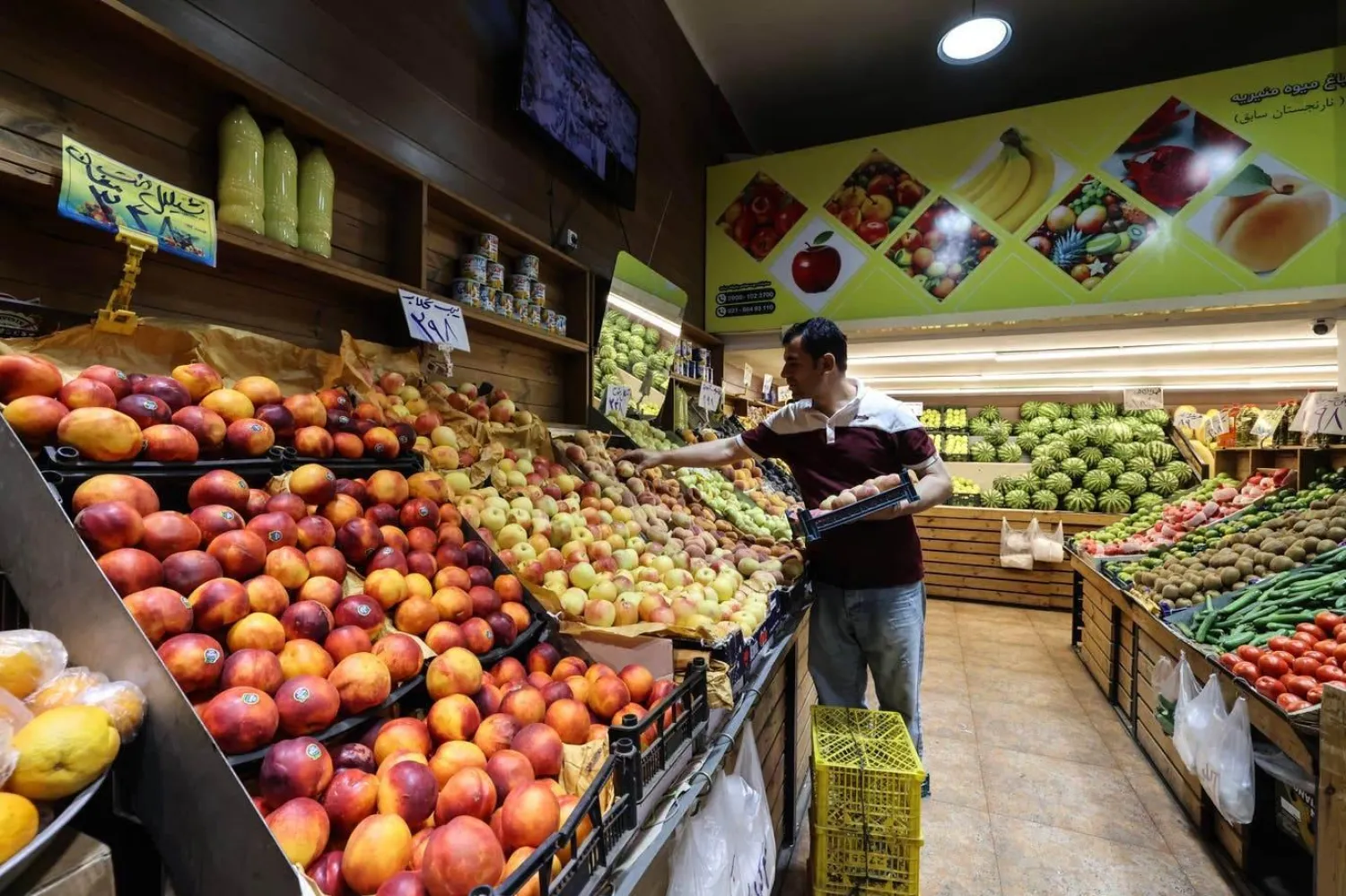 Tahran’ın güneyindeki bir marketteki bir adam meyveleri düzenliyor (AFP)