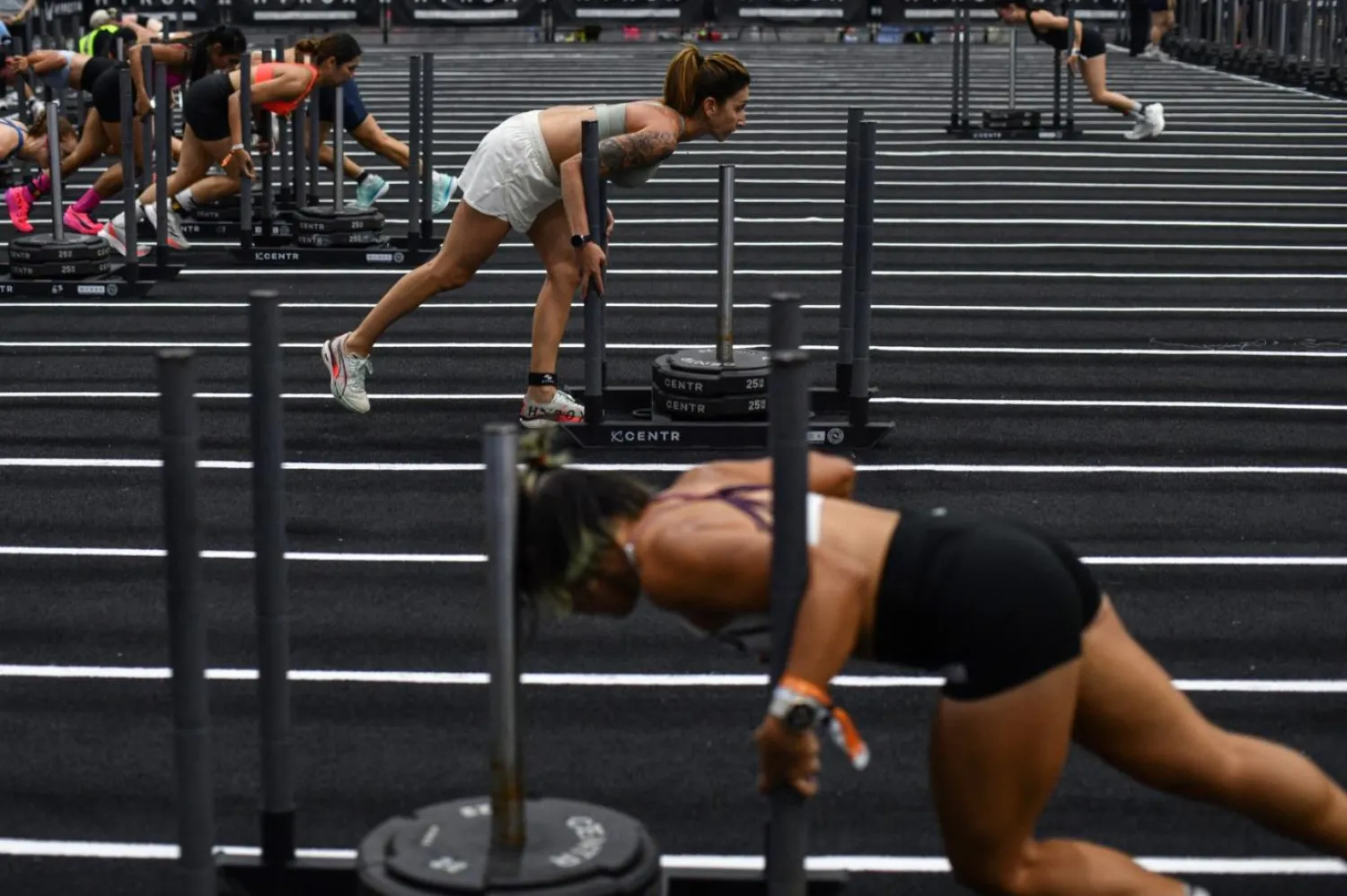 Katılımcılar, bir Hyrox fitness yarışındaki "kızak itme" etabında mücadele ediyor (AFP)