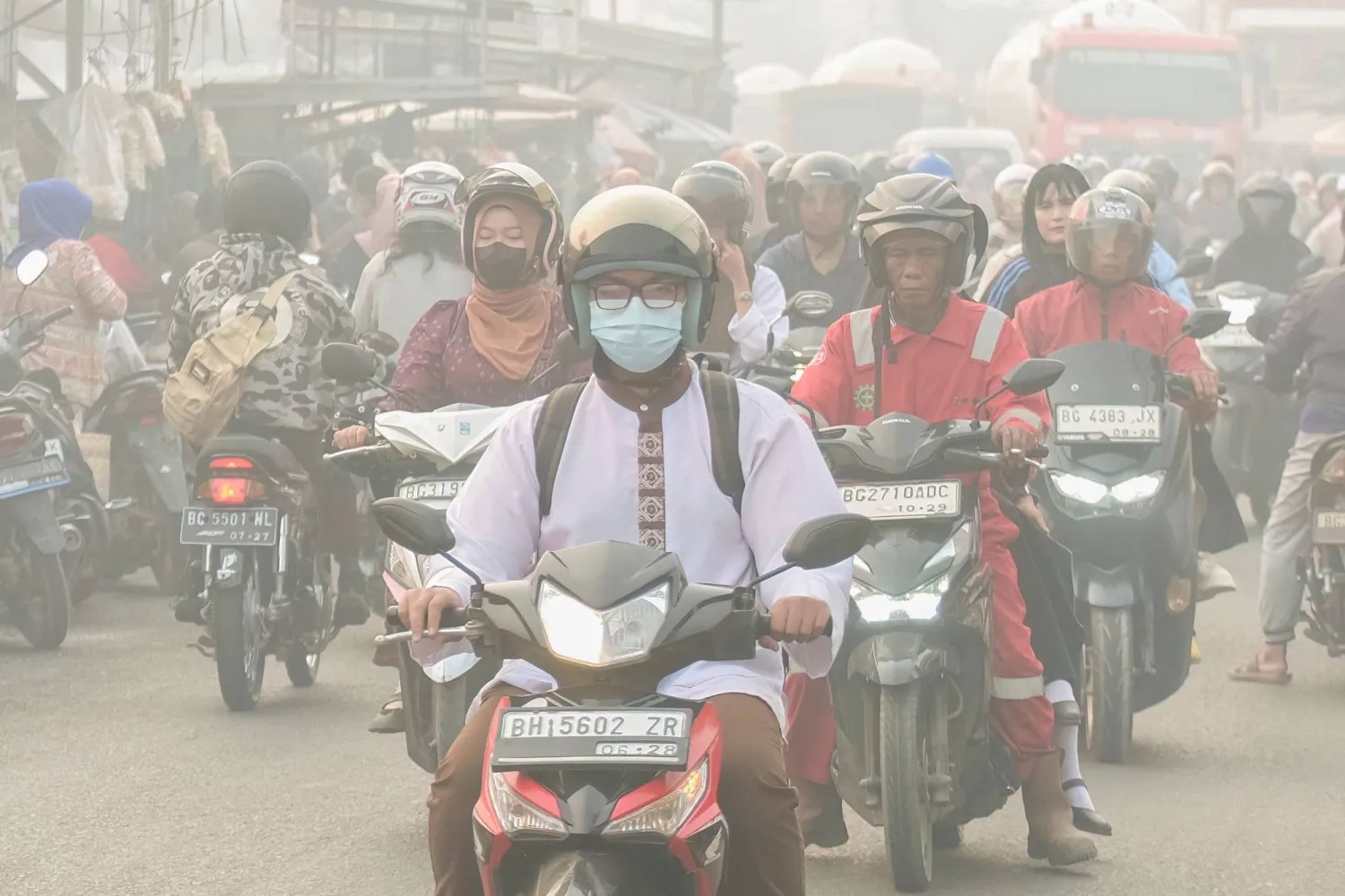 People commute along a road as haze from forest and land fires shrouds Palembang, South Sumatra on October 2, 2026. (Photo by AL ZULKIFLI / AFP)