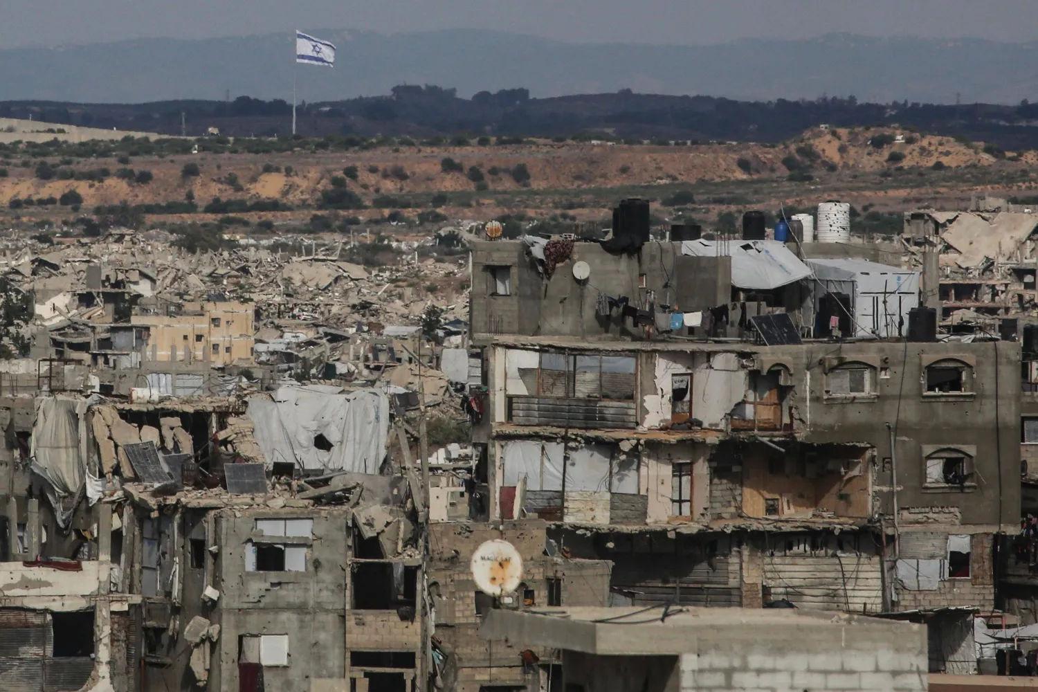 A photograph shows destruction at the Jabalia refugee camp in the northern Gaza Strip, with an Israeli flag fluttering in the background, on October 5, 2026. (AFP)