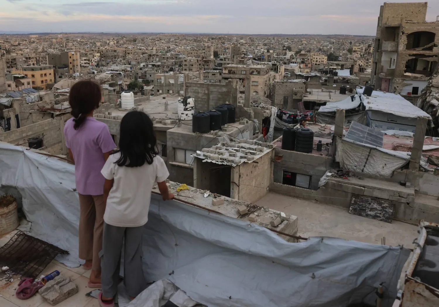أطفال فلسطينيون يقفون أعلى سطح في مخيم جباليا شمال قطاع غزة أمس (أ.ف.ب)