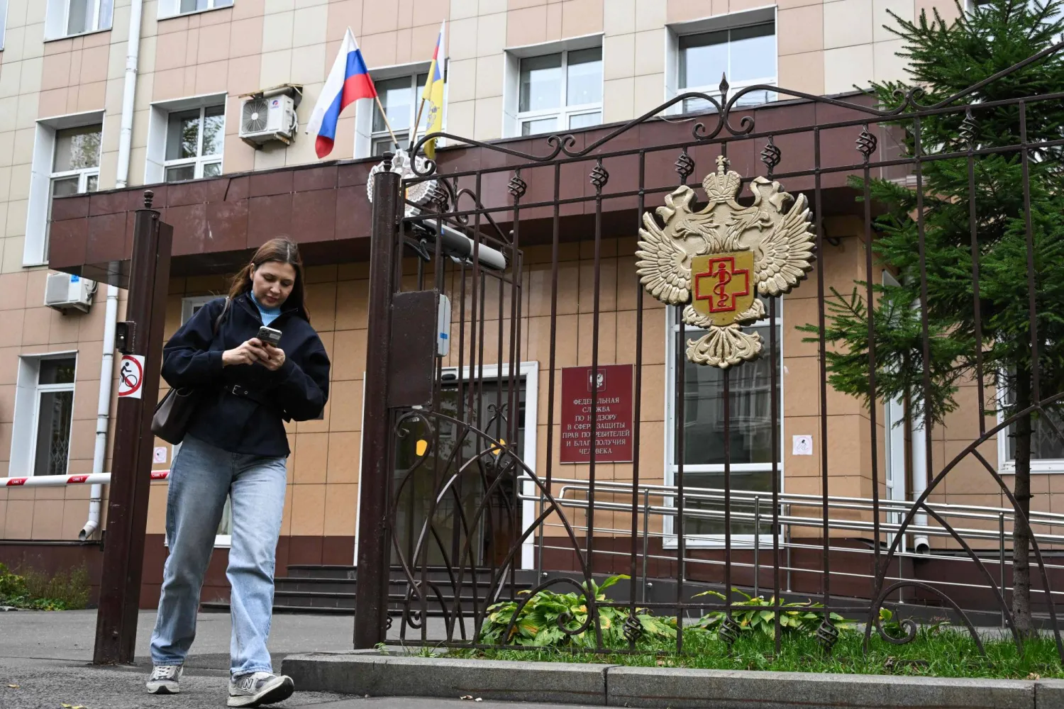 A woman leaves the grounds of the headquarters of Russia's consumer and health watchdog Rospotrebnadzor in Moscow on October 5, 2026. (Photo by Igor IVANKO / AFP)