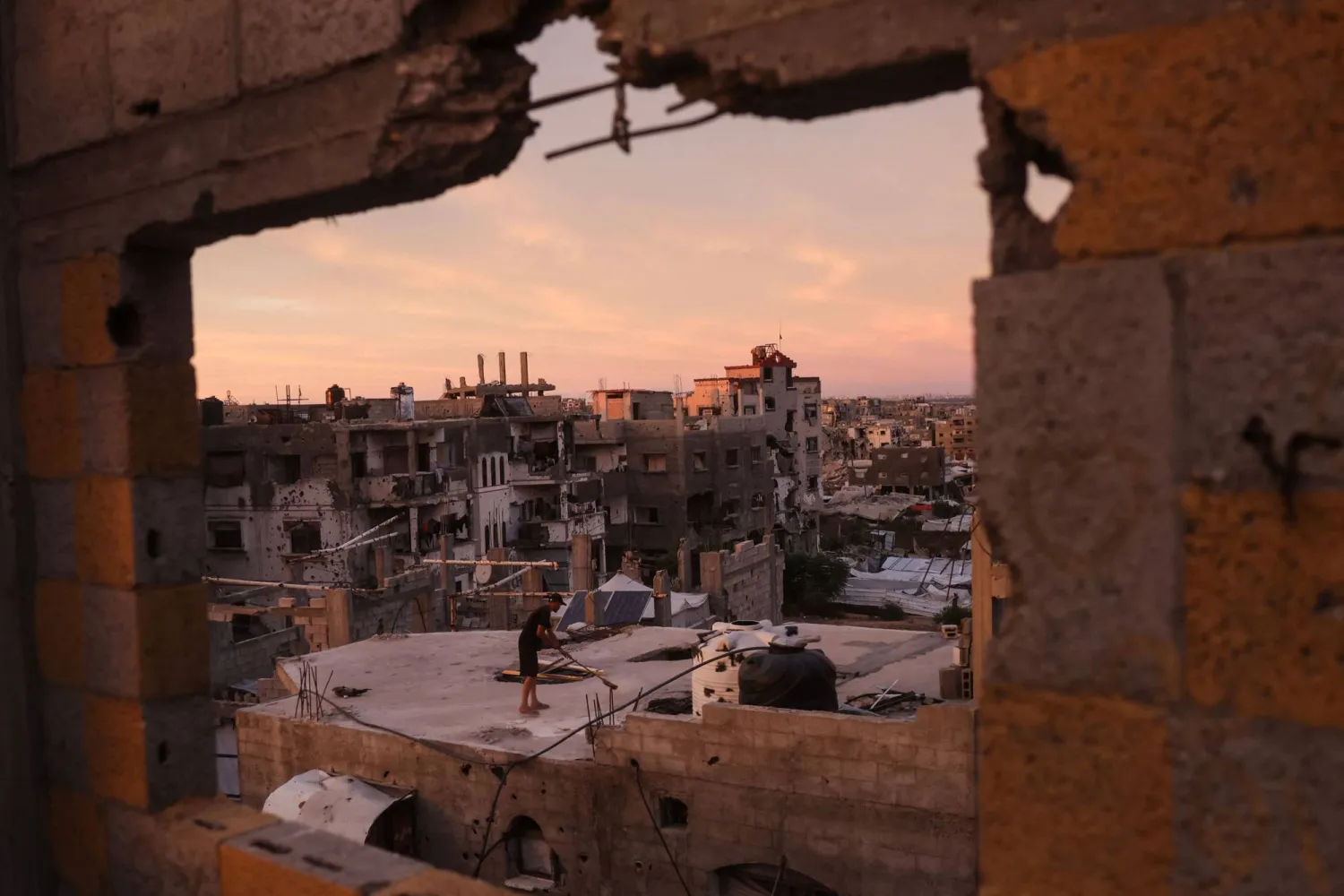 TOPSHOT - A Palestinian man cleans the roof of a building at the Jabalia refugee camp in the northern Gaza Strip on October 5, 2026.  (Photo by Bashar Taleb / AFP) 