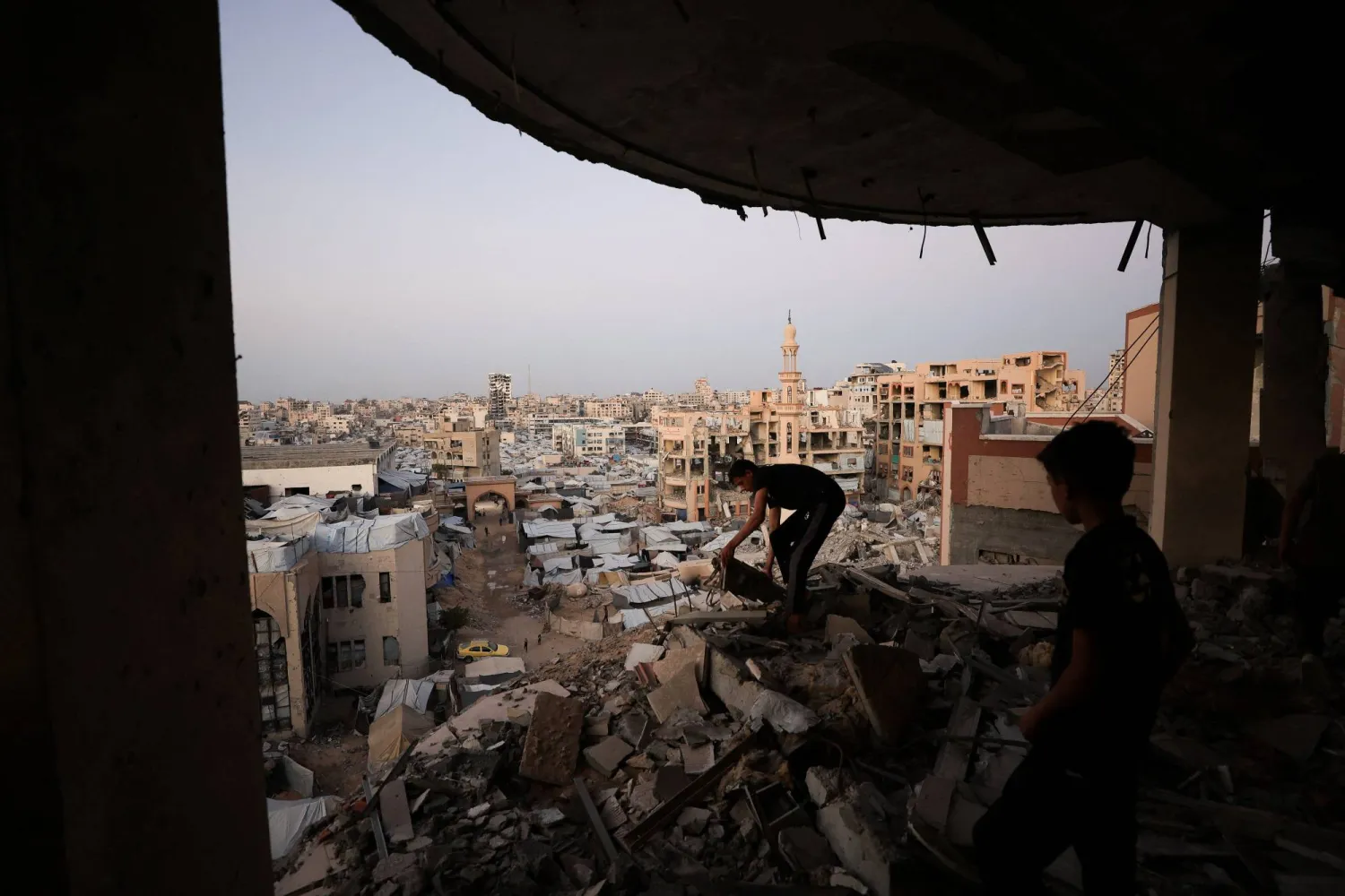 A Palestinian man works amid the rubble of a building damaged during the war, overlooking a makeshift tent camp at the Islamic University, in Gaza City, October 3, 2026. (Reuters) 