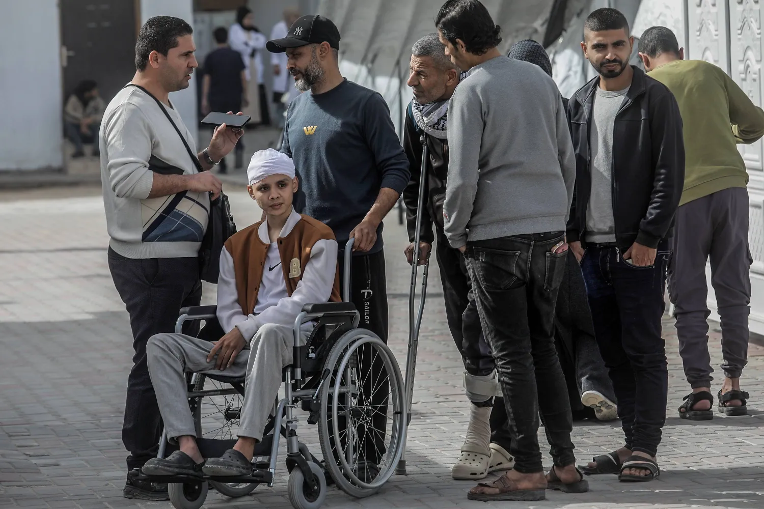 مرضى فلسطينيون ينتظرون في ساحة مستشفى الهلال الأحمر لإجلائهم من قطاع غزة عبر معبر رفح الحدودي مع مصر لتلقي العلاج في فبراير الماضي (د.ب.أ)