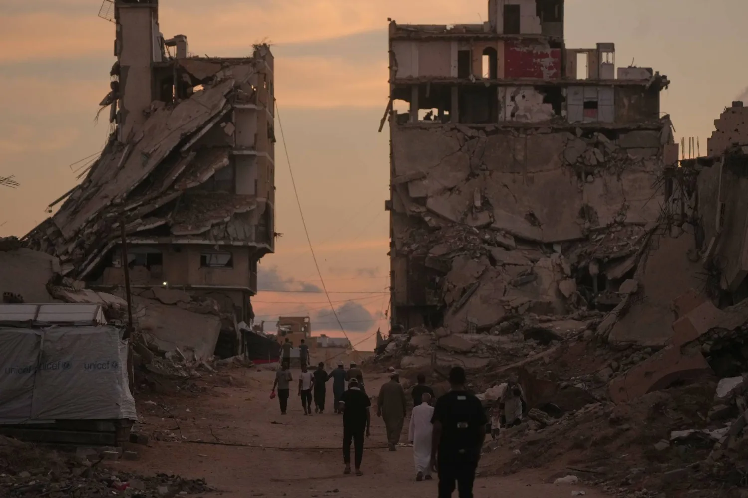 Palestinians walk along a street surrounded by buildings destroyed in Israeli military strikes during the Israel-Hamas war in Gaza City, Tuesday, Oct. 6, 2026. (AP Photo/Jehad Alshrafi)