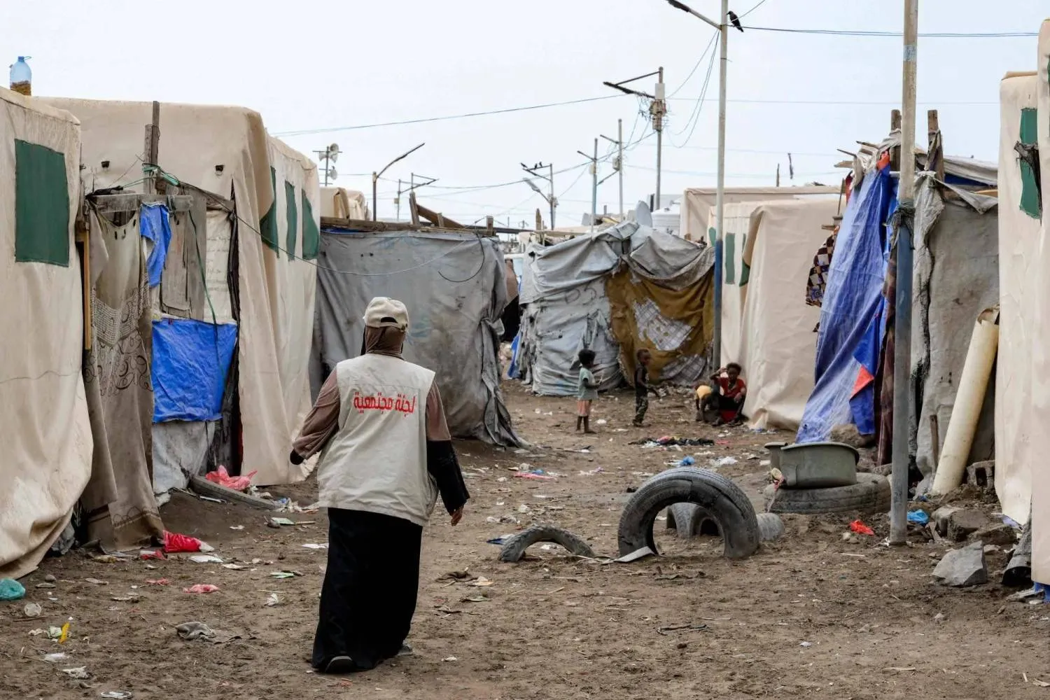 A relief worker walks among the tents at a temporary shelter for displaced people north of Aden (AFP)