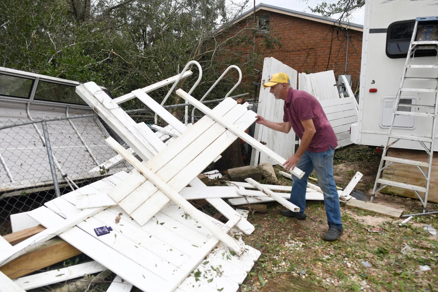 Curt Brown picks up debris left by Isaias around his RV home on Saturday, Oct. 10, 2026, in Milton, Fla. (AP Photo/Octavio Jones)