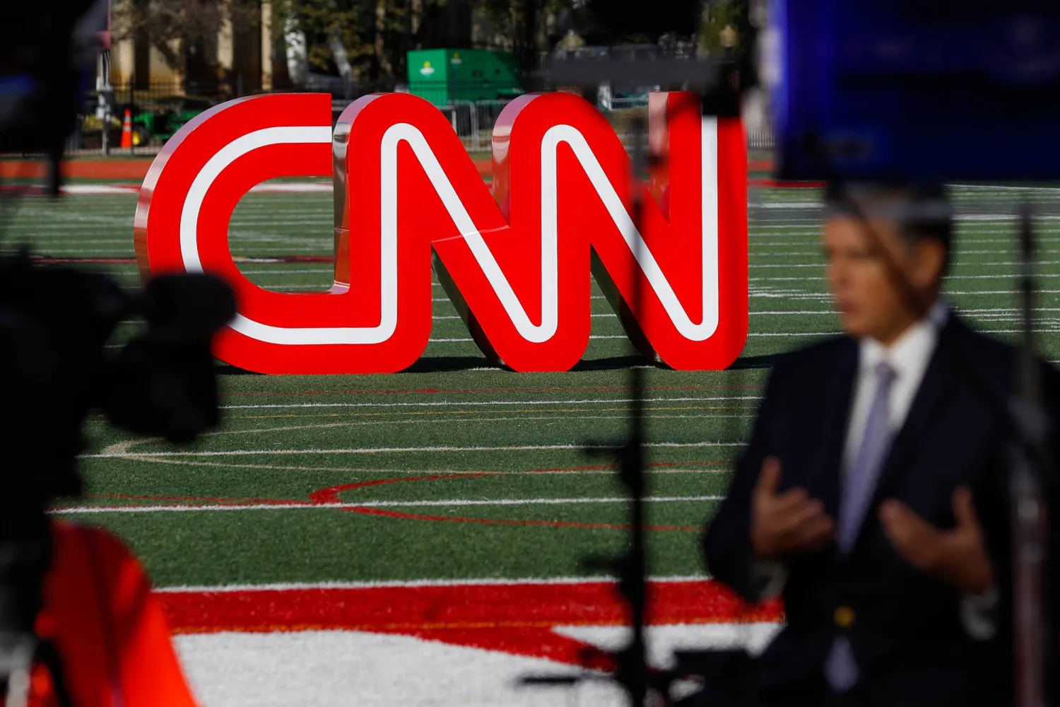 صحفي يسجل مقطع فيديو بالقرب من لافتة لشبكة "سي إن إن" (CNN) (أ.ب)