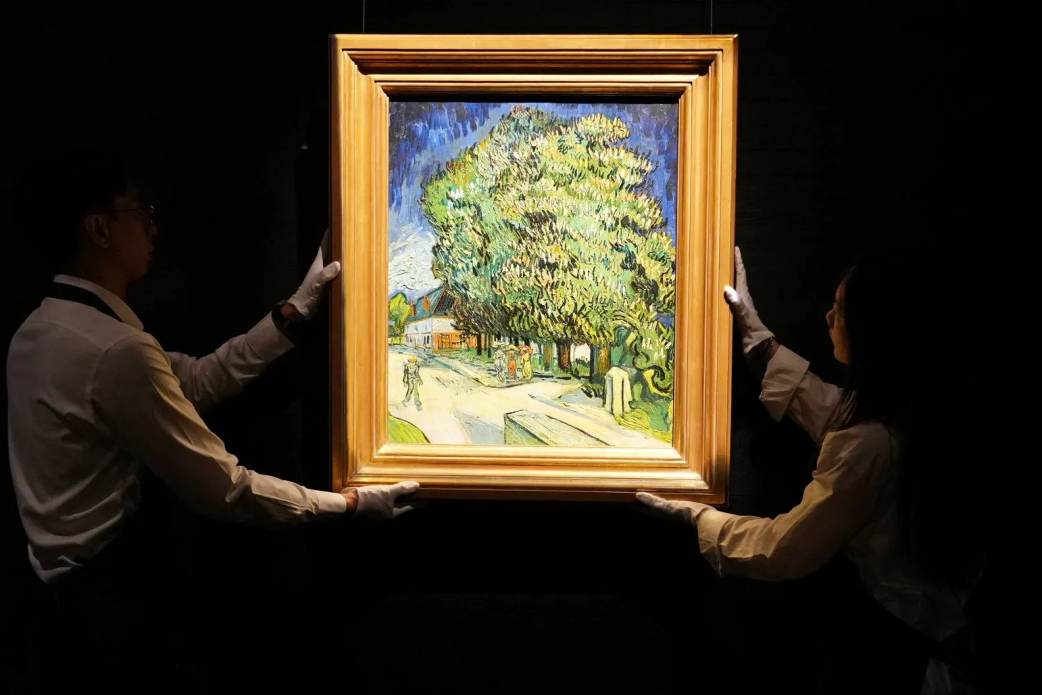 Staff members pose with Vincent van Gogh's "Chataigniers en fleurs" (Chestnut Trees in Blossom) at a media preview ahead of its auction in New York, at Sotheby's in Hong Kong, China, October 13, 2026. REUTERS/Joyce Zhou