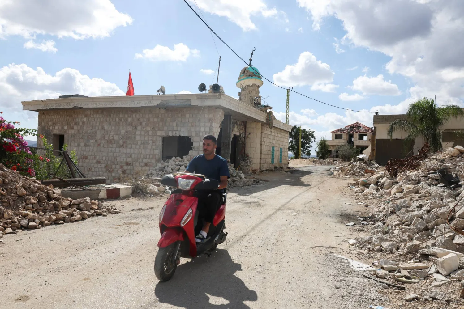 A man rides his motorcycle next to damaged buildings in West Zawtar, southern Lebanon, October 1, 2026. REUTERS/Mohamed Azakir