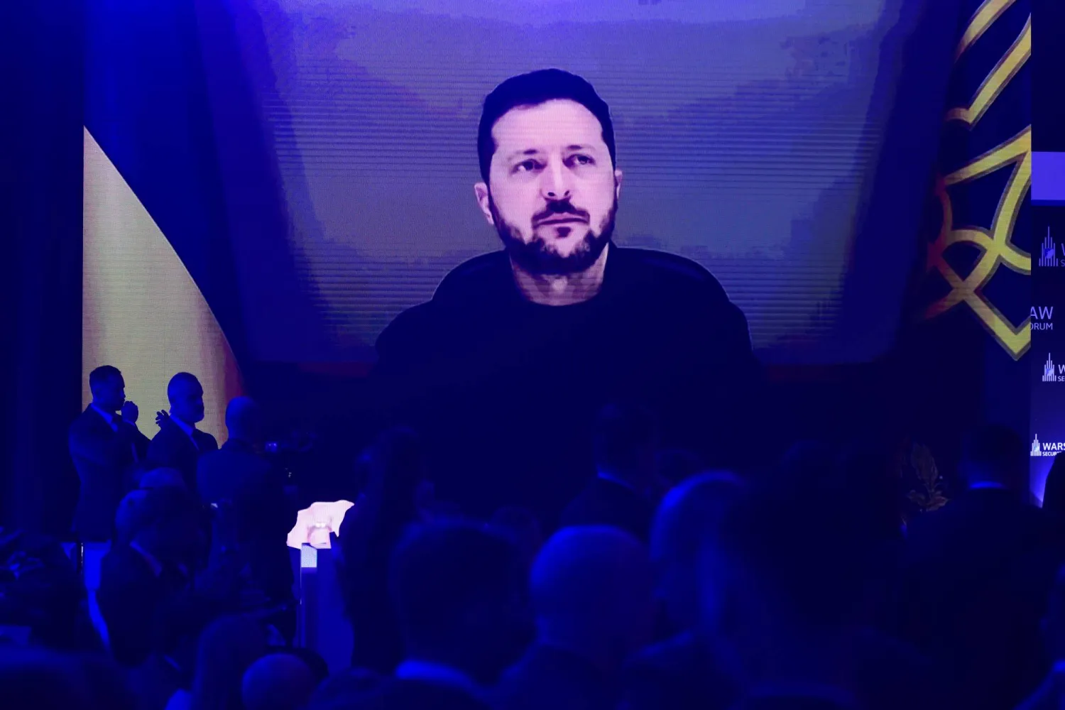People watch Ukrainian President Volodymyr Zelenskyy on a large screen as he speaks to the Warsaw Security Forum in Warsaw, Poland, Monday, Oct. 12, 2026. (AP)