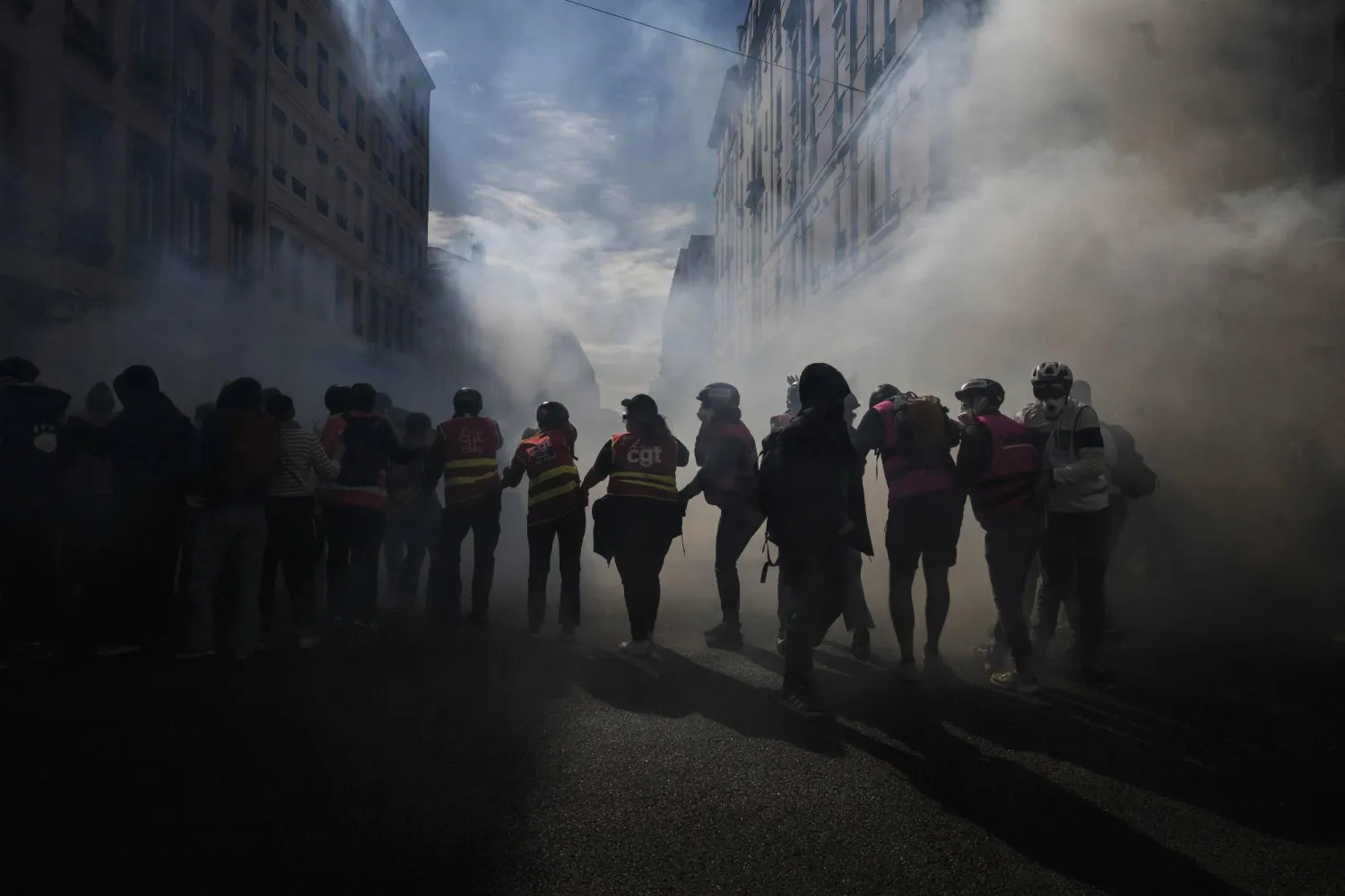 CGT unionists stand amid tear gas fired by riot police during a demonstration of high-school students in Lyon, southeastern France on October 13, 2026, as part of a nationwide high school mobilization. (AFP)