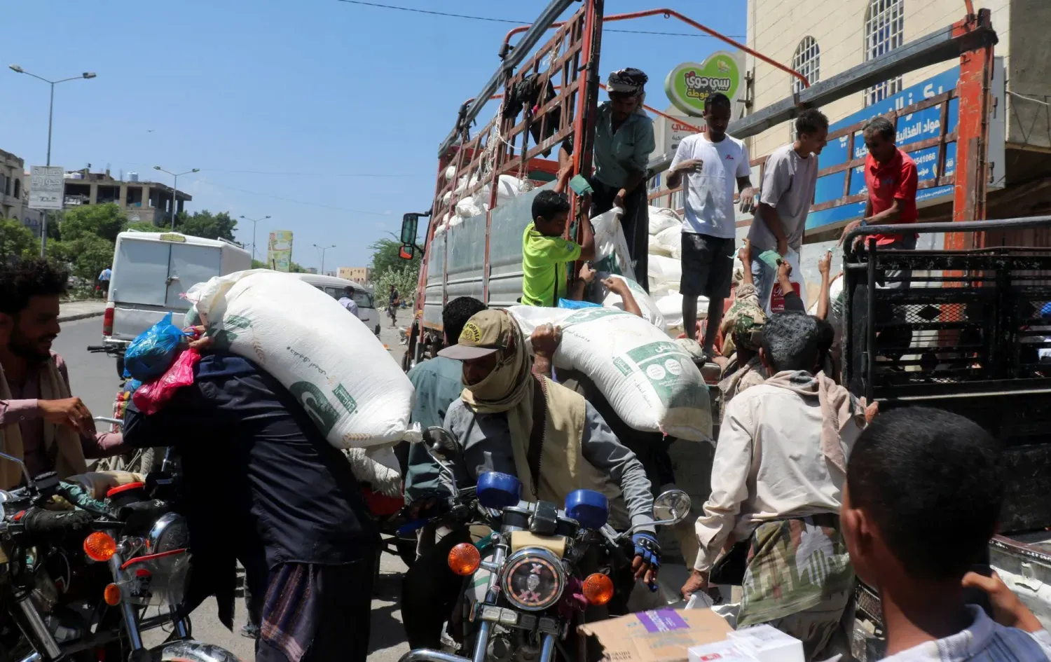 Husilerin kuşatması altındaki Taiz’de bir grup kişi, kamyondan buğday unu indiriyor (Reuters)