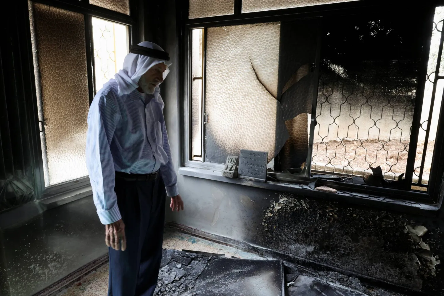 فلسطيني يتفقد الأضرار في مسجد أحرقه مستوطنون إسرائيليون في قرية مخماس قرب رام الله بالضفة الغربية الأربعاء (رويترز)