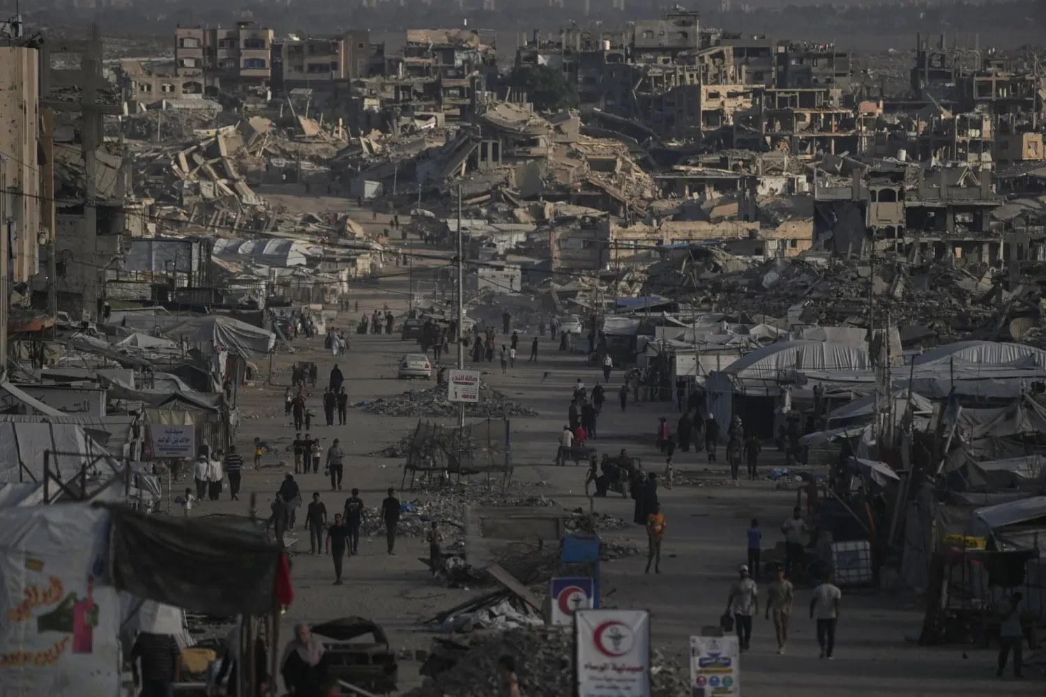 Gazze şehrinde yıkılmış binaların arasında yürüyen Filistinliler (AP)