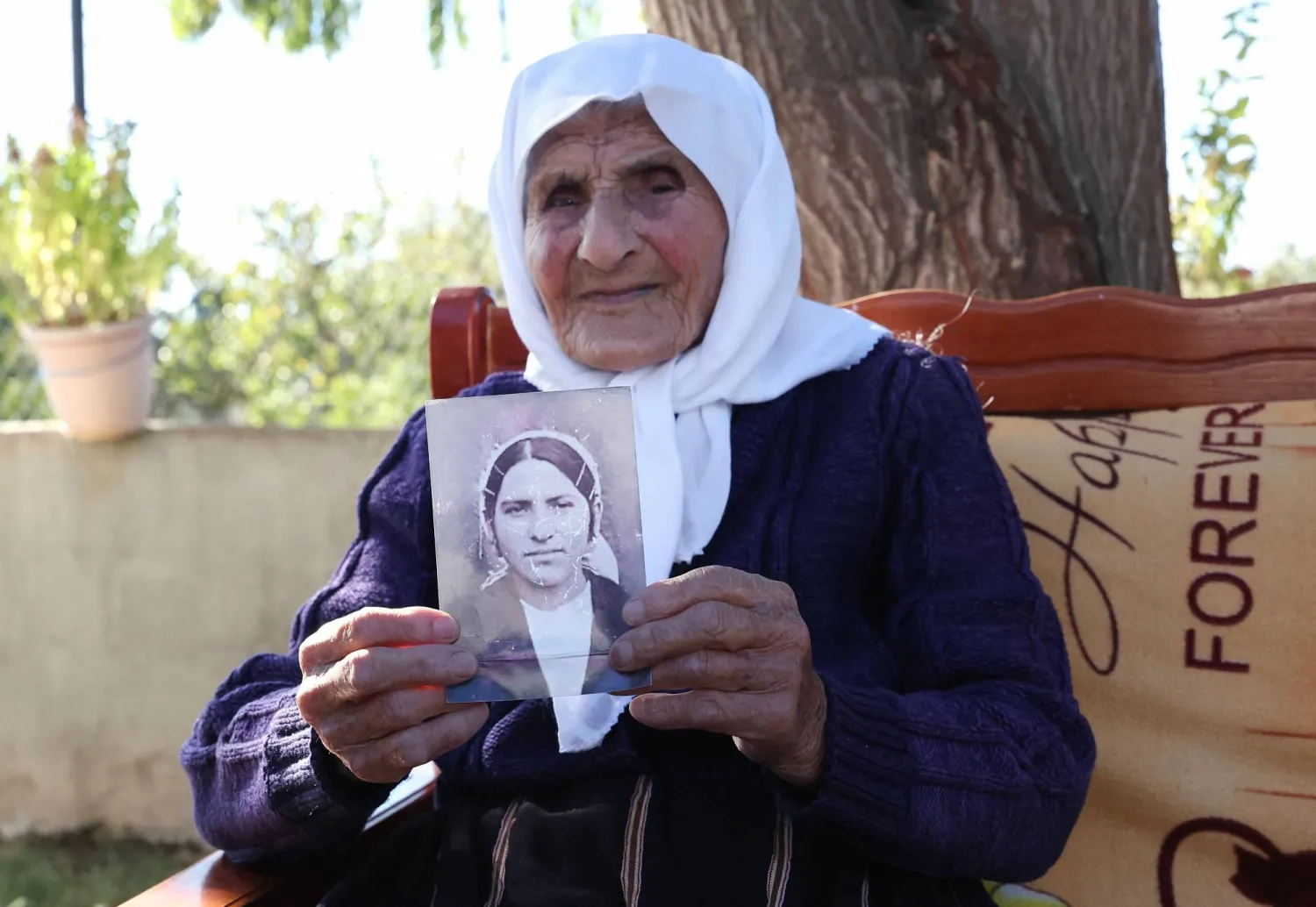 The 117-year-old Qamile Marra holds a black and white photograph from her youth during an interview with AFP in the garden of her home in the village of Ferras, near Kucove, some 80 kilometres from the capital Tirana on October 3, 2026. (Photo by Adnan Beci / AFP)