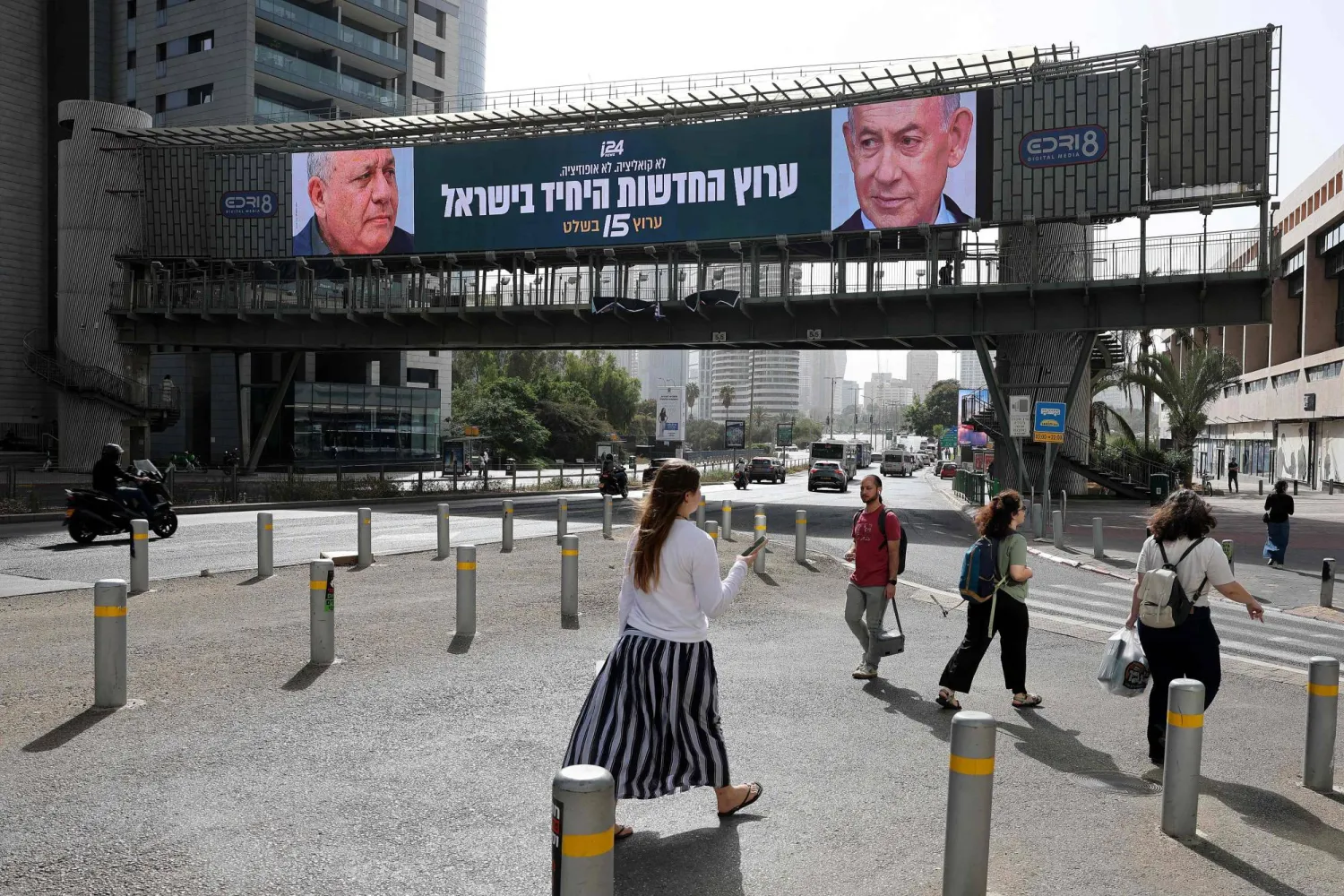 People walk past a banner featuring Israel's Prime Minister Benjamin Netanyahu (R) of the Likud party and country's former chief of the general staff and leader of the Yashar centrist political party Gadi Eisenkot in Ramat Gan on October 15, 2026. (AFP) 