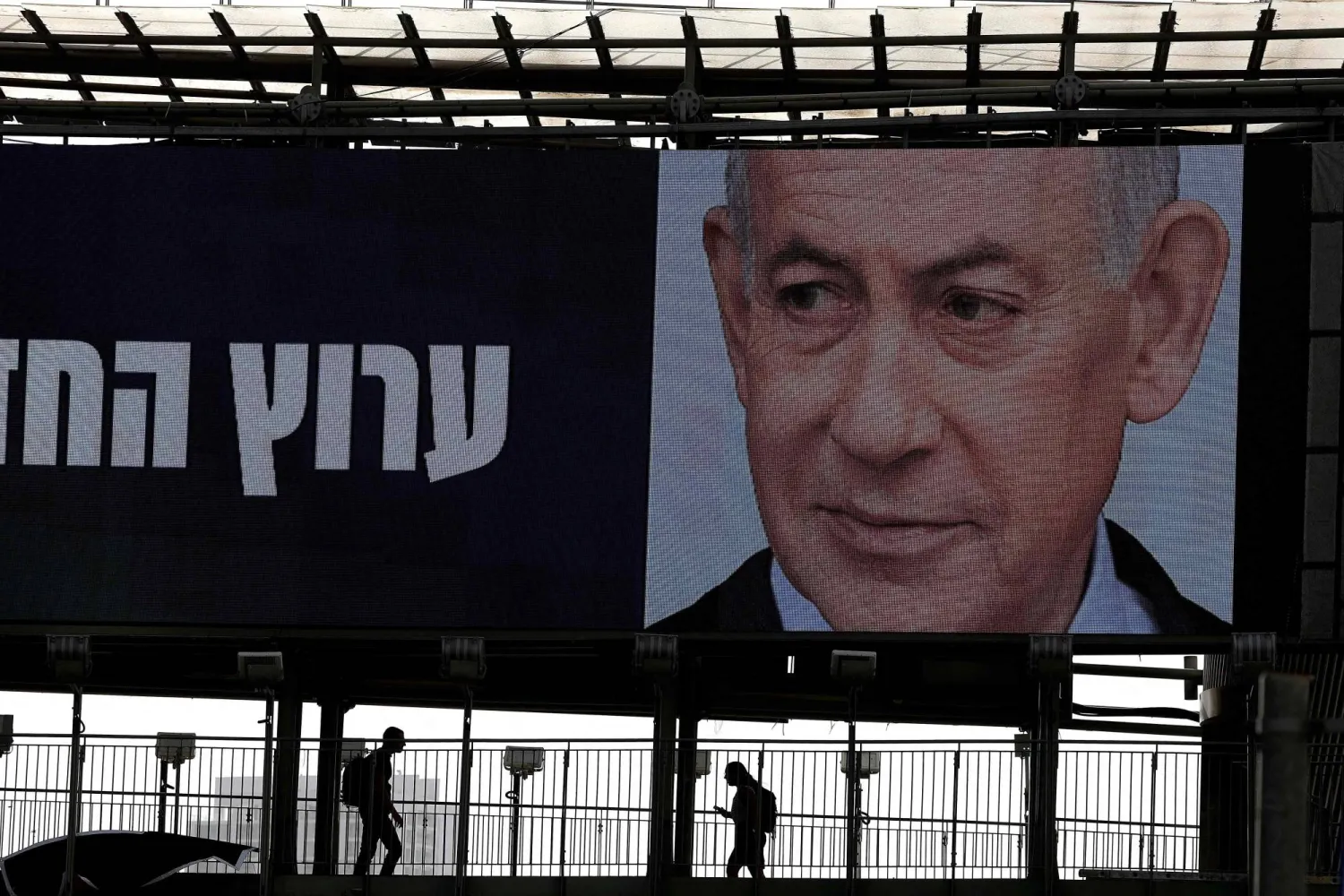 People walk under a giant election billboard bearing a portrait of Israeli Prime Minister Benjamin Netanyahu's Likud party in Ramat Gan, on October 15, 2026. (AFP)