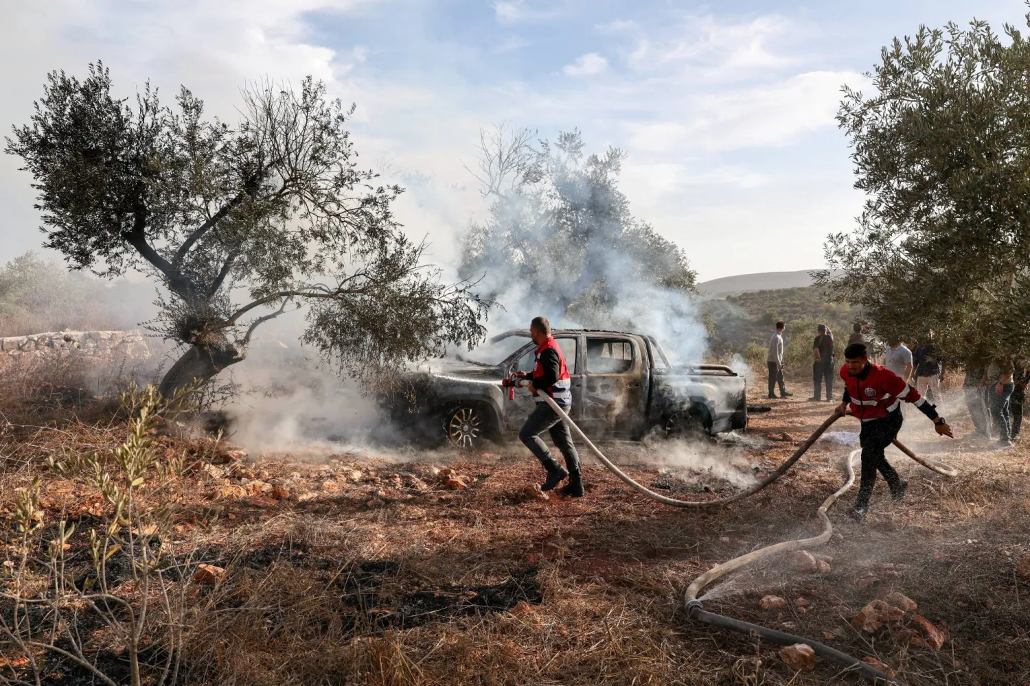 Firefighters douse a burnt car with water after Israeli militant settlers attacked a group of Palestinians harvesting olives near Turmus Ayya in the Israeli-occupied West Bank, October 16, 2026. REUTERS/Ammar Awad 