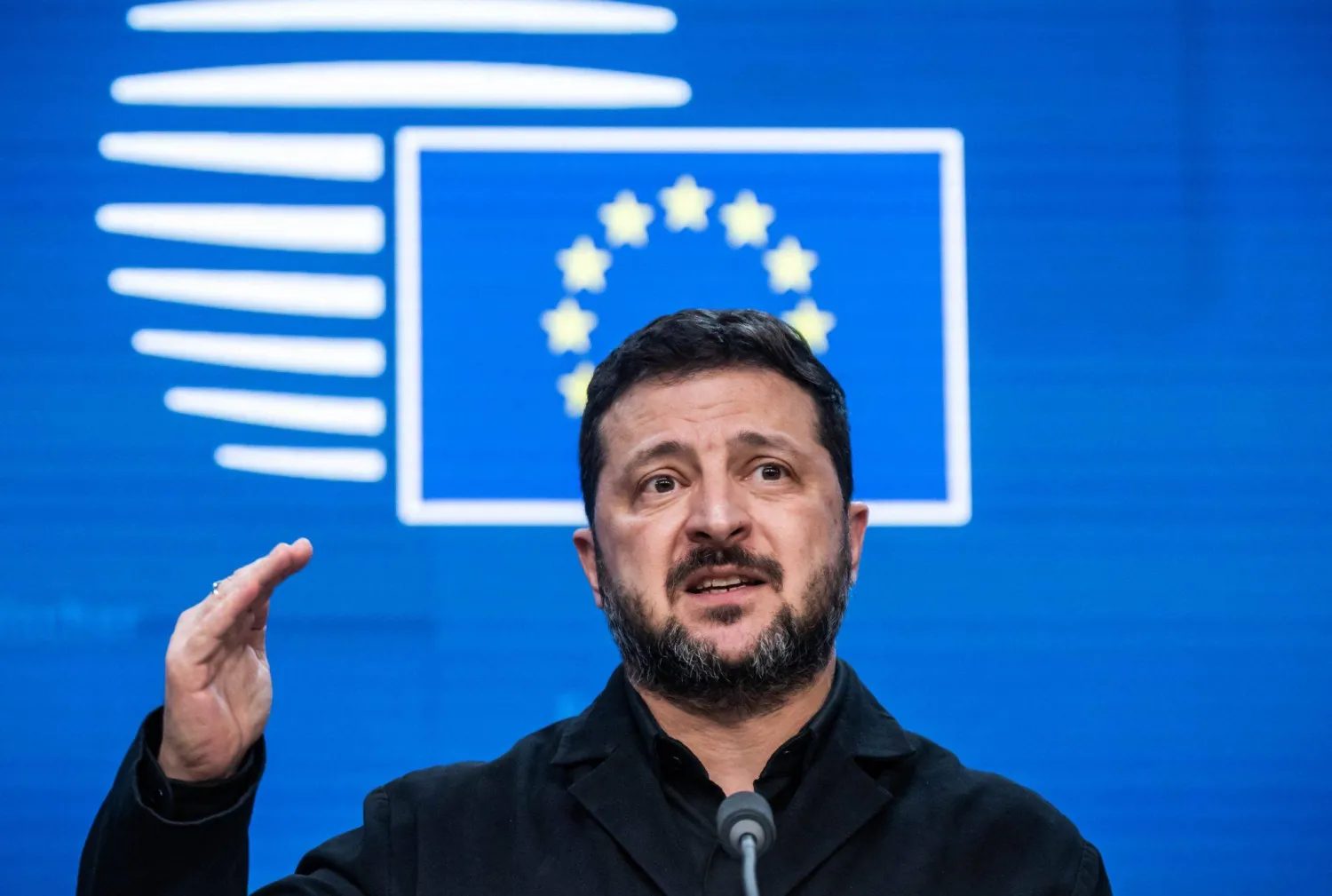 الرئيس الأوكراني فولوديمير زيلينسكي وخلفه شعار الاتحاد الأوروبي على هامش قمة لزعماء التكتل (د.ب.أ)