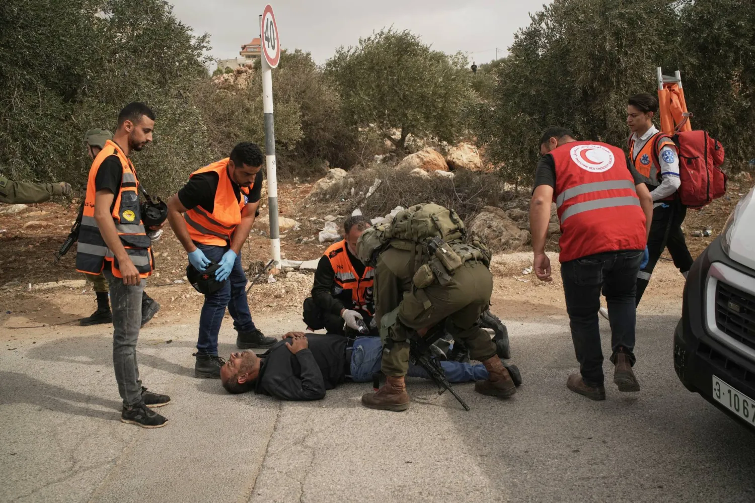 مسعفون فلسطينيون يعاينون رجلاً أصابه رصاص إسرائيلي في الضفة الغربية بعد اعتداء مستوطنين على قاطفي الزيتون في قرية خربة أبو فلاح (أ.ب)