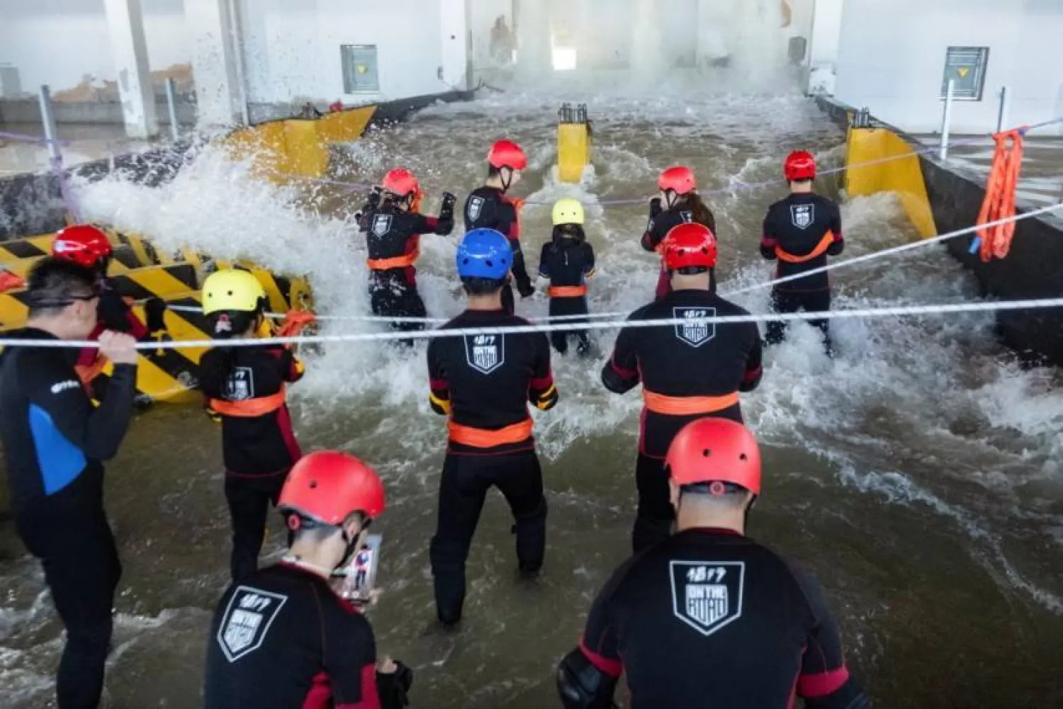 Participants brace for surging water in a flash flood simulator at the Lvxing center in Hangzhou (Reuters)