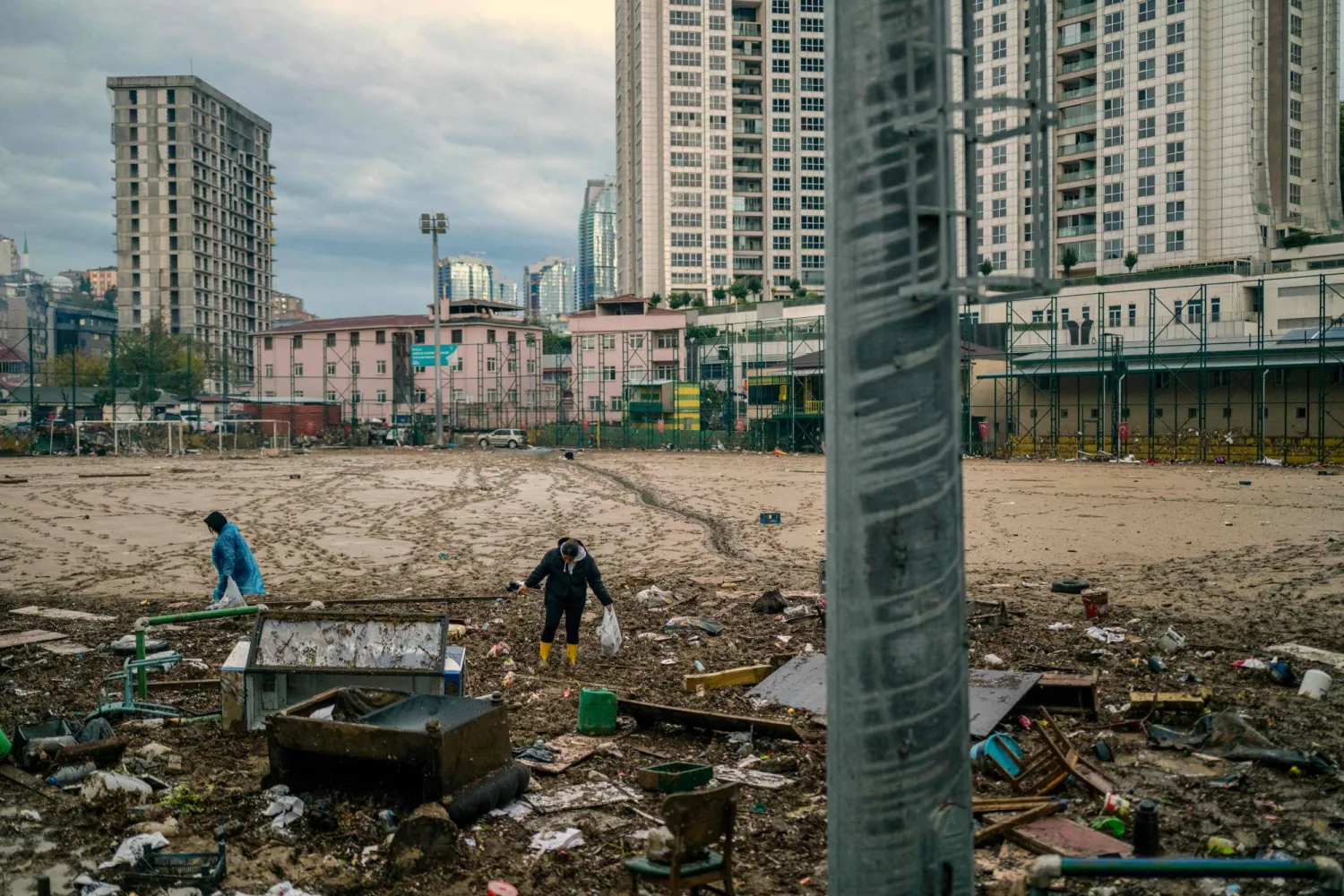 Women work to clean debris on a football pitch covered with mud one day after heavy rain caused flooding in the Ayazaga district of Istanbul on October 16, 2026. (AFP)