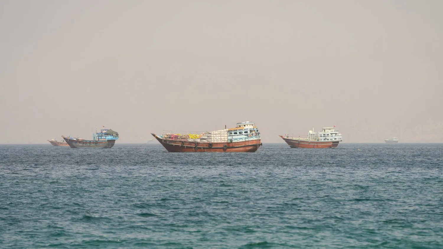 سفن تعبر مضيق هرمز كما تبدو من شبه جزيرة مسندم العُمانية يوم الاثنين (رويترز)