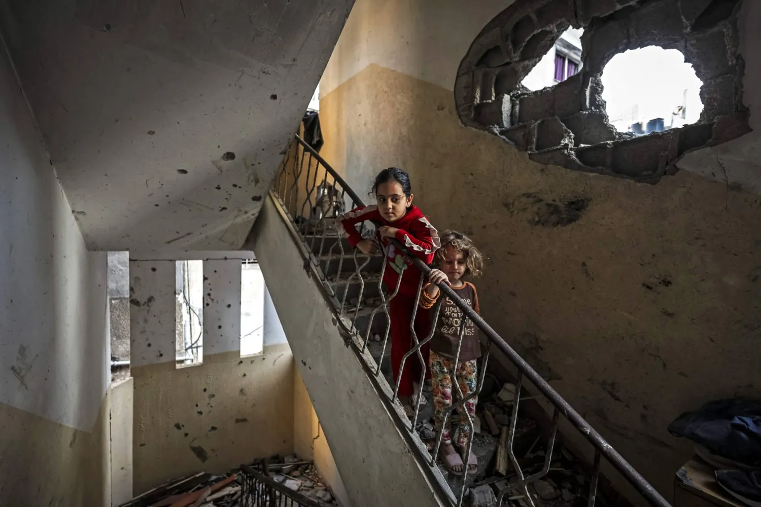 Children stand at the site of an Israeli strike on a residential building that killed two people in Gaza City on October 20, 2026. (AFP)