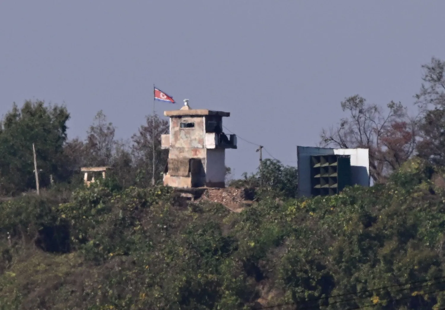 A North Korean guard post (C) and a giant loudspeaker (R) on the North side of the Demilitarized Zone (DMZ) dividing the two Koreas, are seen from the border city of Paju on October 20, 2026. (AFP) 