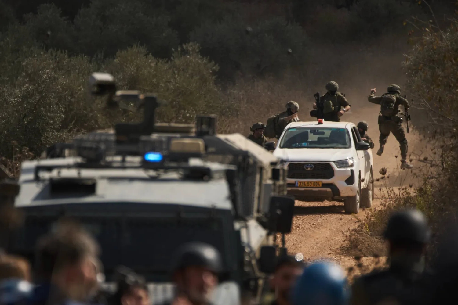 قوات إسرائيلية تصل إلى طريق مغلق يمنع الفلسطينيين من الوصول إلى بساتينهم لقطف الزيتون في بلدة ترمسعيا بالضفة الغربية يوم الأربعاء (أ.ب)