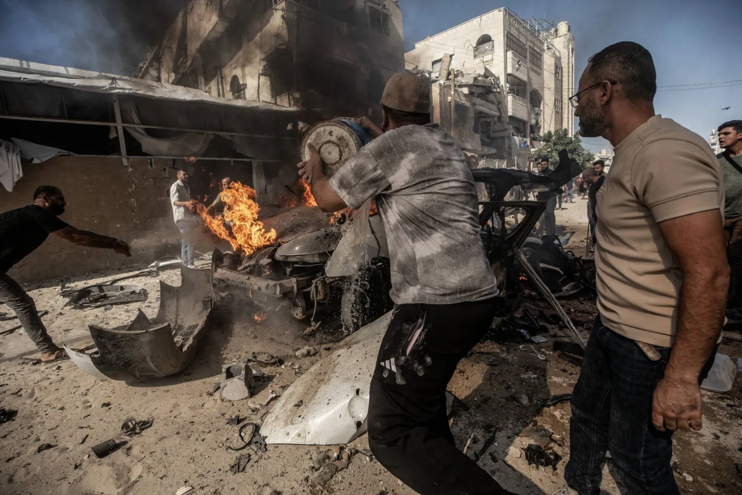 فلسطينيون يحاولون إخماد حريق في مركبة دُمرت جراء غارة جوية إسرائيلية جنوب مدينة غزة الخميس (إ.ب.أ)