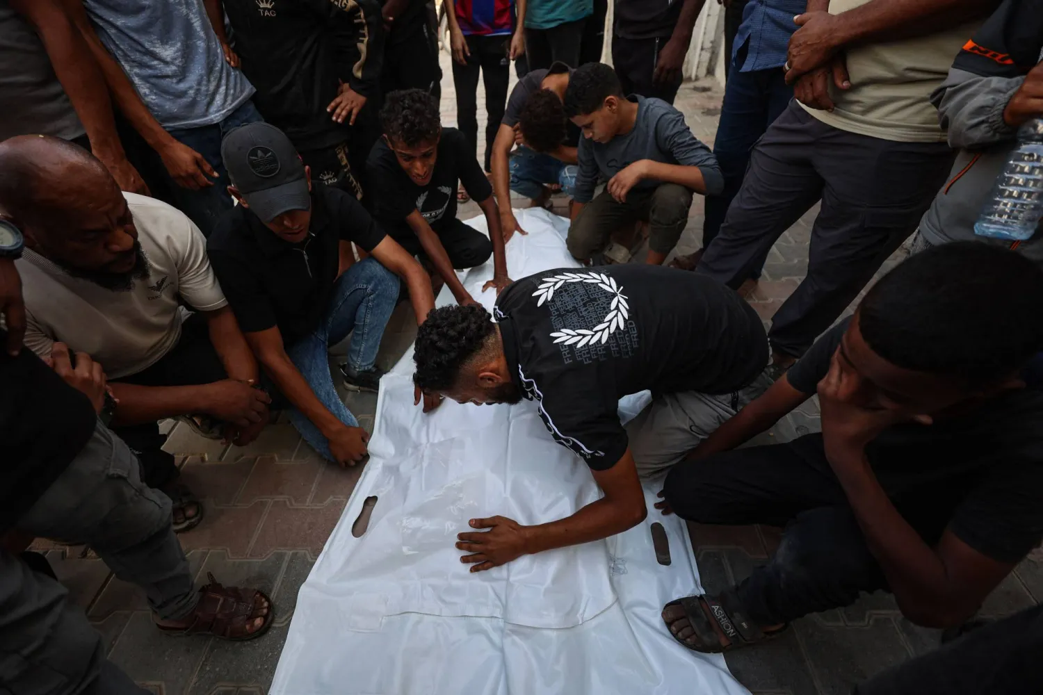 Mourners grieve over the bodies of three Palestinians during their funeral at Al Shifa Hospital in Gaza City on October 25, 2026, after they were killed in an Israeli strike on the Islamic University building. (Photo by Omar AL-QATTAA / AFP)