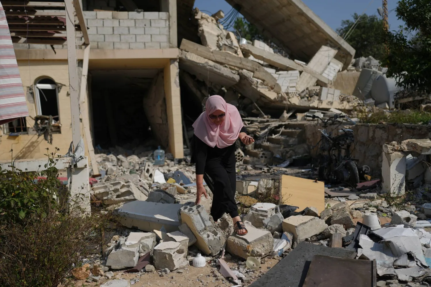 Visual artist Lina Jouni searches through rubble for fragments of Israeli munitions that struck a house in the southern Lebanese town of Roumine (AP)