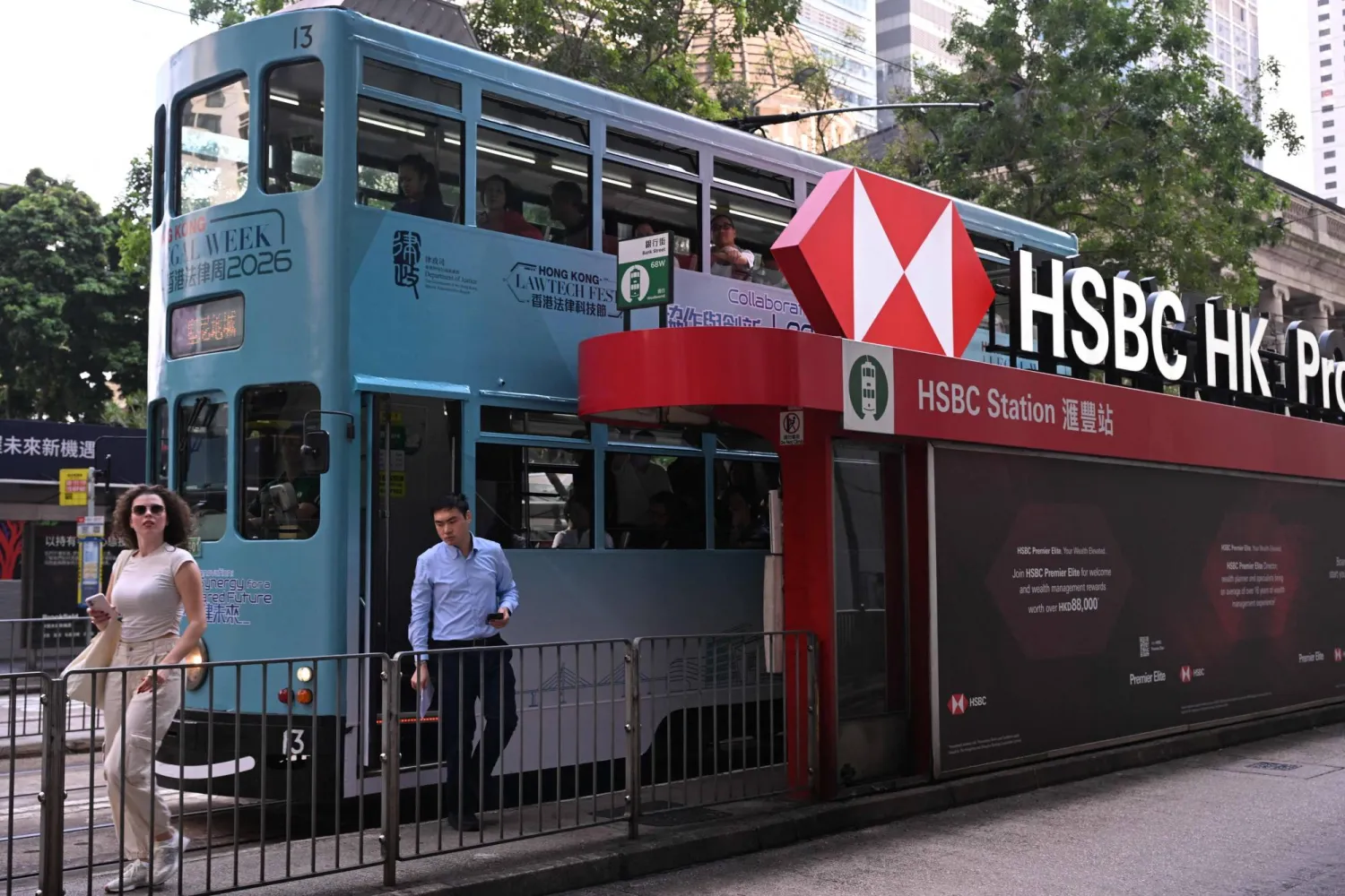 People alight from a tram outside the HSBC bank headquarters in Hong Kong on October 27, 2026, ahead of the bank's third quarter results announcement. (Photo by Peter PARKS / AFP)